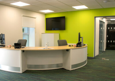 Reception at Kingdom House. Curved front desk with green wall and a large screen.