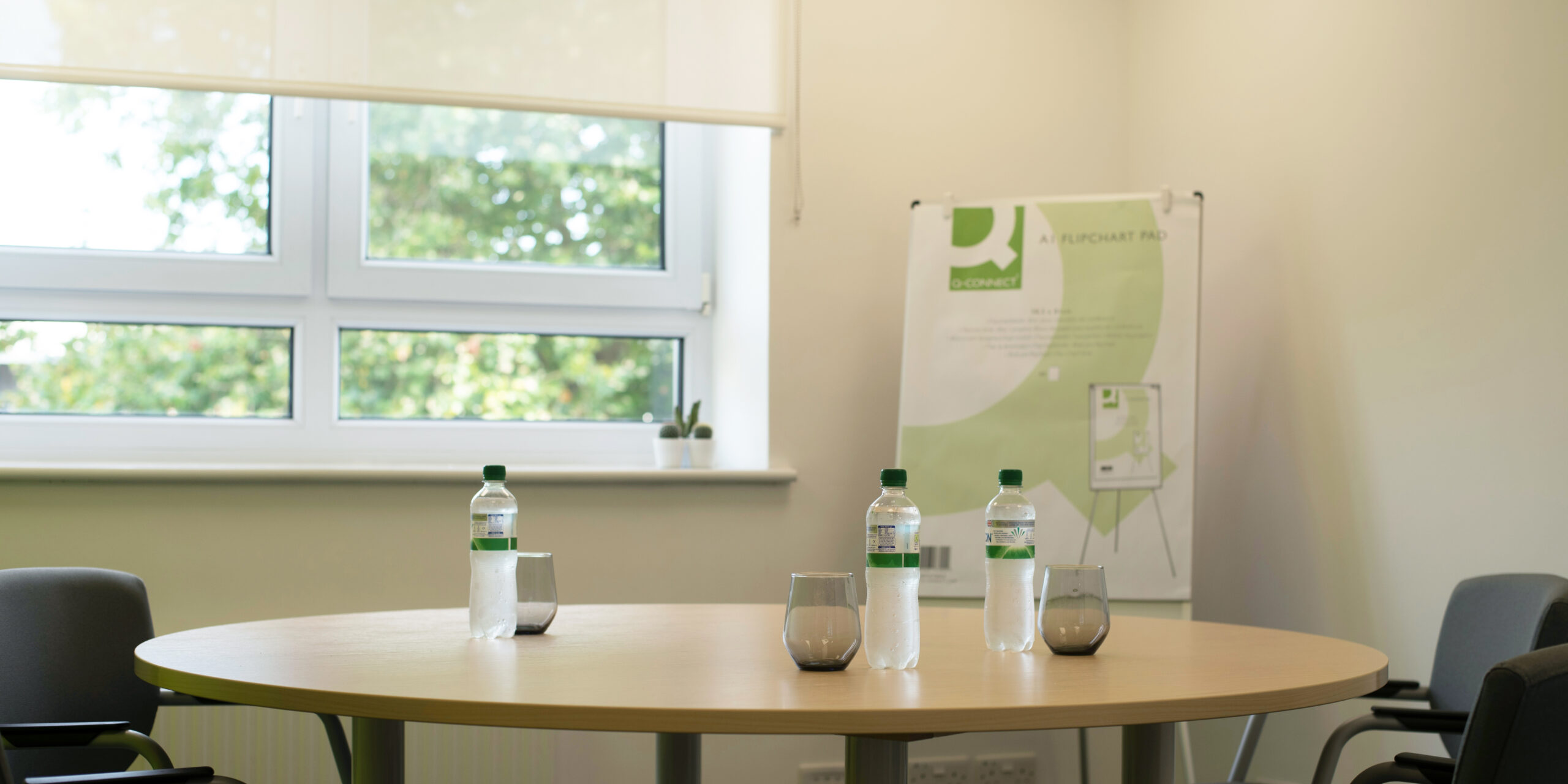 Round table with water and glasses. FLipchart paper next to the window.