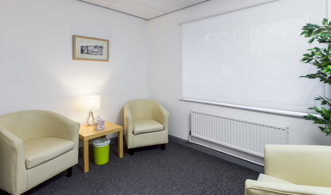 Small relaxed room with cream coloured "bucket" style arm chairs.