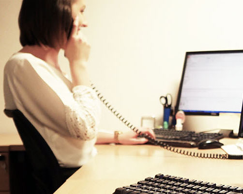 A lady sat at her desk on the phone